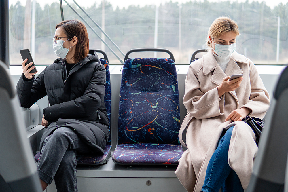 Duas mulheres usando máscaras cirúrgicas em transporte público